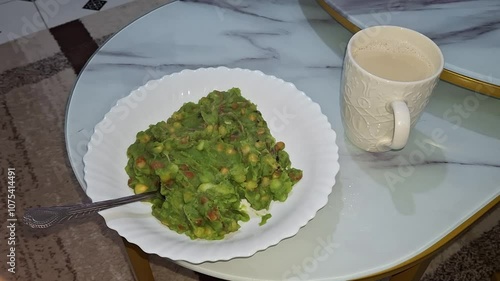 Enjoying a hearty green pea and vegetable mash with a cup of tea on a cozy table in a well-decorated room