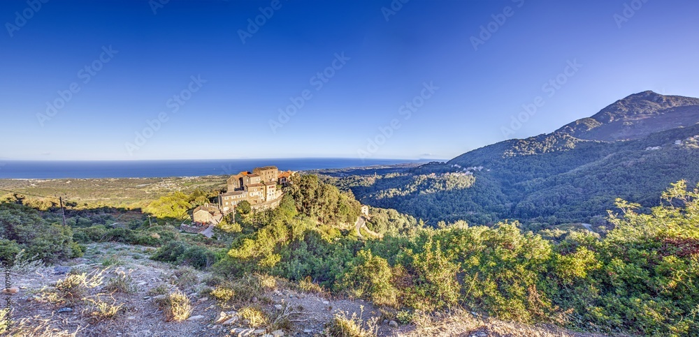 Panoramic view of a traditional Corsican mountain village with the vast eastern coastline in the distance Panoramic view of a traditional Corsican mountain village with the vast eastern coastline in the distance