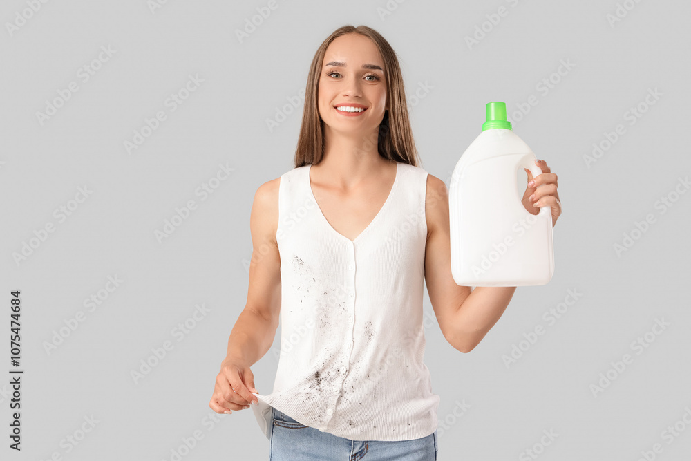 Young woman in dirty clothes with stain remover on light background Young woman in dirty clothes with stain remover on light background