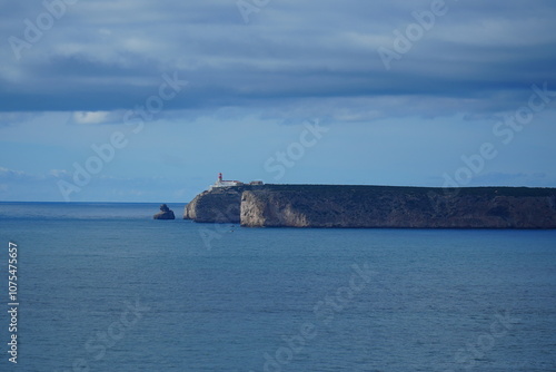 The rocky headland and the lighthouse at the Cap of Sao Vicente at the south-west end of Europe, open sea to the Atlantic Ocean. View from the fortress Sagres, Algarve, Portugal.