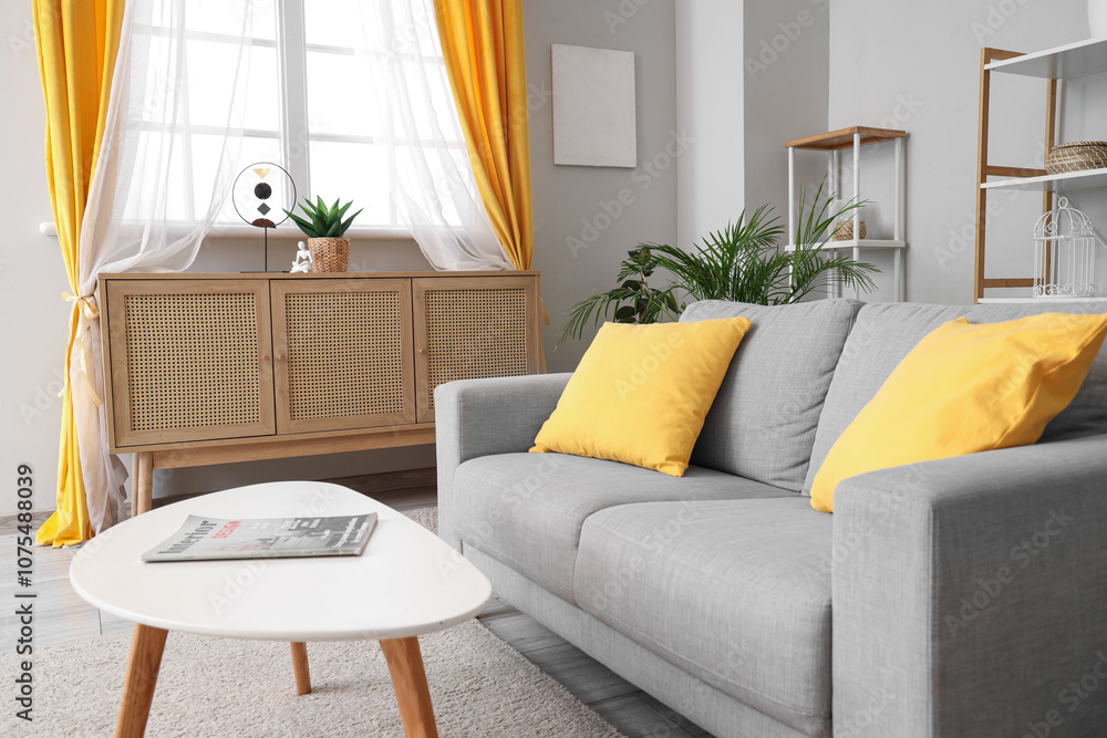 Fototapeta premium Interior of light living room with sofa, commode and curtains on window