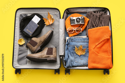 Valokuva Open packed suitcase with clothes, accessories, shoes and autumn leaves on yello
