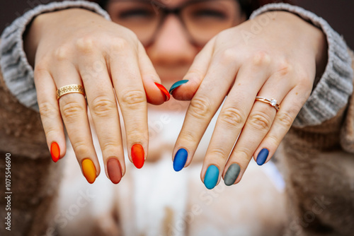Fotografía a woman showing off her vibrant, multicolored manicure while wearing rings