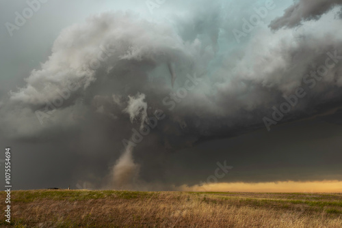 A thin, beautiful tornado spins across a dirt field in southeastern Wyoming during a Summer storm.