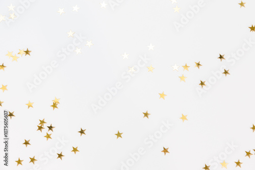 Gold sparkle confetti stars on a white background. Glitter, shine, bright. Christmas festive flat lay, winter holiday, new year, happy birthday concept. Banner for greeting card, top view, copy space.