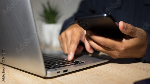 Businessman using smartphone and typing on laptop keyboard for cybersecurity and privacy