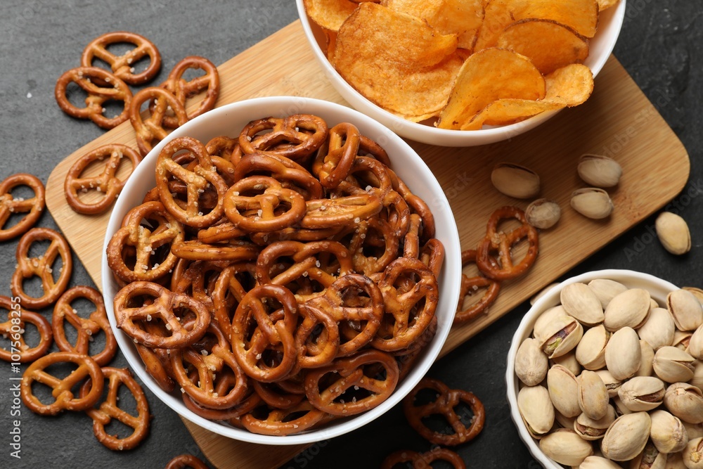 Delicious pretzel crackers and other snacks on black table, flat lay Delicious pretzel crackers and other snacks on black table, flat lay