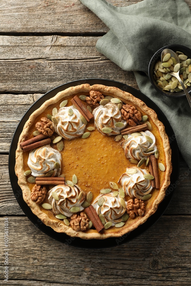 Homemade pumpkin pie with whipped cream, seeds and cinnamon on wooden table, top view Homemade pumpkin pie with whipped cream, seeds and cinnamon on wooden table, top view