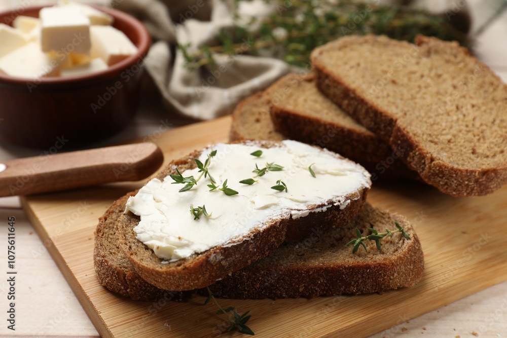 Fresh bread with butter, thyme and knife on light table, closeup Fresh bread with butter, thyme and knife on light table, closeup