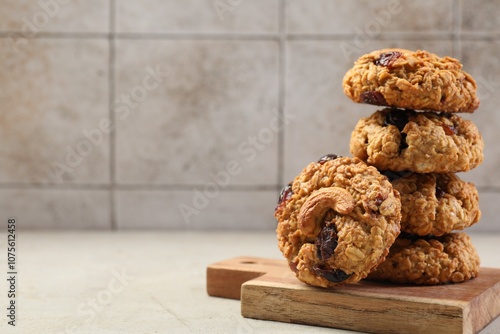 Delicious oatmeal cookies with raisins and nuts on light grey table, space for text photo