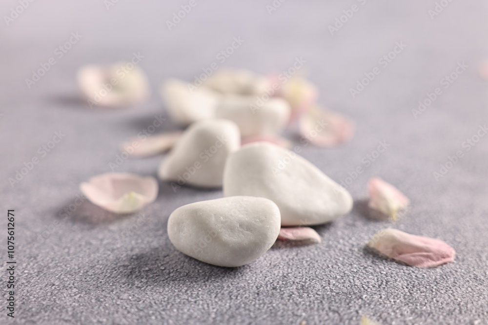 Spa stones and petals on grey table, closeup Spa stones and petals on grey table, closeup