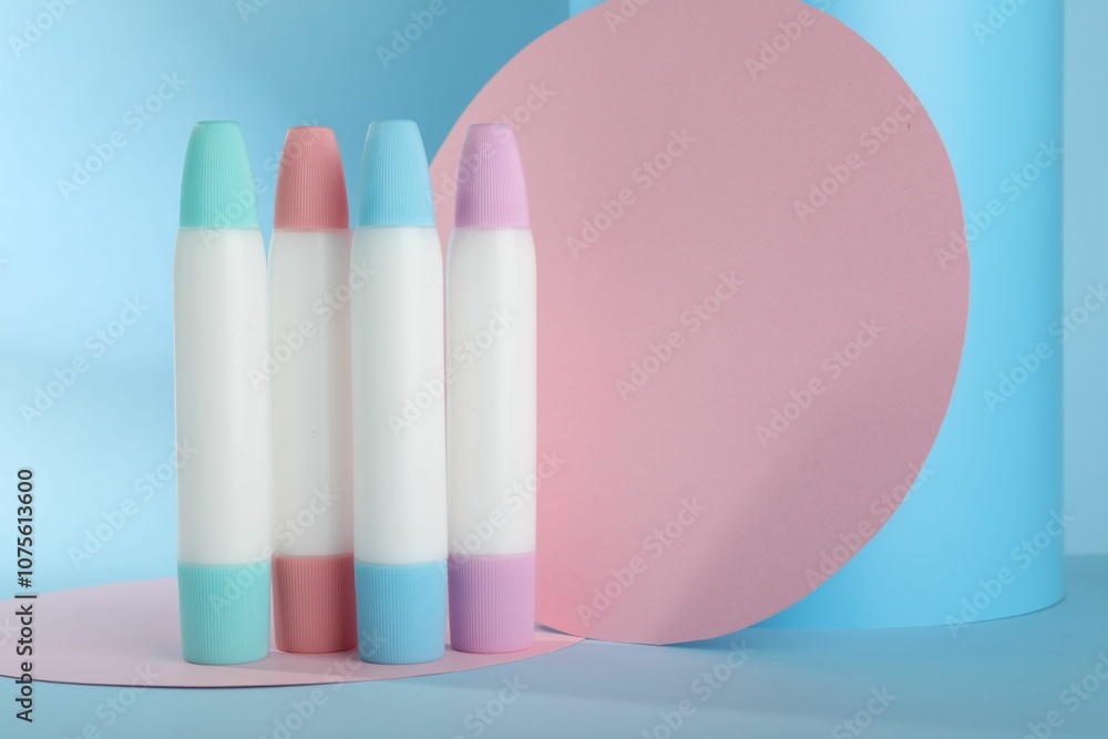 Many different glue sticks and paper cutouts on light blue background Many different glue sticks and paper cutouts on light blue background