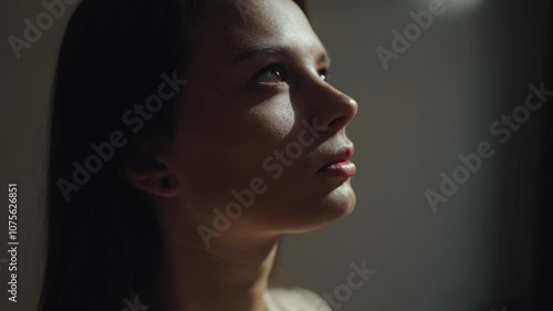 Close portrait of a young beautiful, attractive woman in the dark with the rays of the sun in her eyes, emphasis on facial features, study, work, reflections, fatigue, melancholy, depression, eye