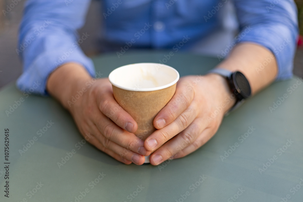 man's hands hold a paper cup of coffee on the table man's hands hold a paper cup of coffee on the table