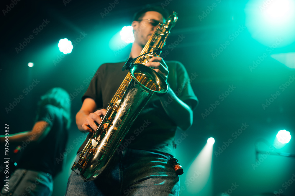 Fototapeta premium Saxophonist performing live on stage with teal lighting