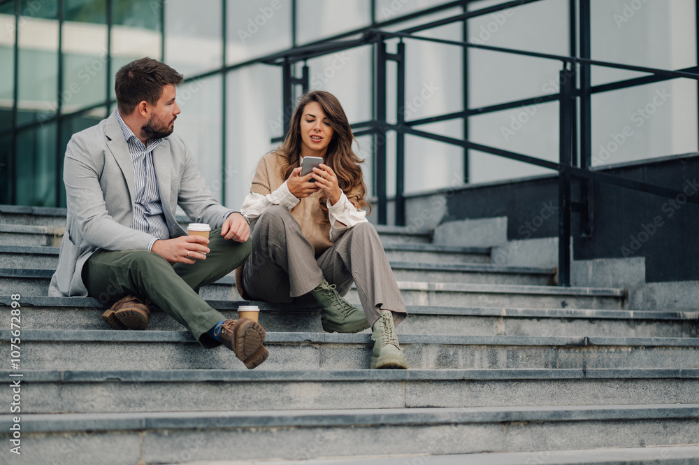 Fototapeta premium Business people taking break and relaxing on stairs with smartphone and coffee