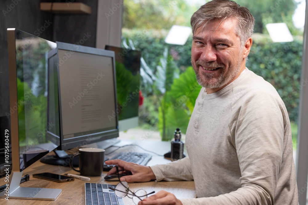 portrait d'un employé de bureau ou d'un homme d'affaires qui est assis à son bureau devant son ordinateur il est souriant et sympathique. Il est heureux de travailler chez lui à distance portrait d'un employé de bureau ou d'un homme d'affaires qui est assis à son bureau devant son ordinateur il est souriant et sympathique. Il est heureux de travailler chez lui à distance