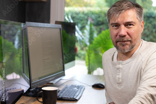 portrait d'un employé de bureau ou d'un homme d'affaires qui est assis à son bureau devant son ordinateur il est souriant et sympathique. Il est heureux de travailler chez lui à distance photo