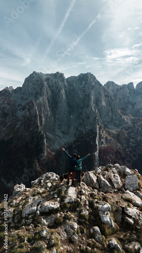 Young couple with two dogs - German and Australian shepherds traveling in Prokletije Mountains, Montenegro. Aerial top view. Hiking in the mountains in the autumn season.