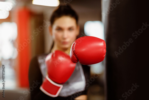 Personal defense class. Beautiful sportswoman in gym, focus on boxing glove photo