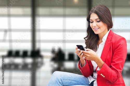 Happy female using smart phone at airport departure area.