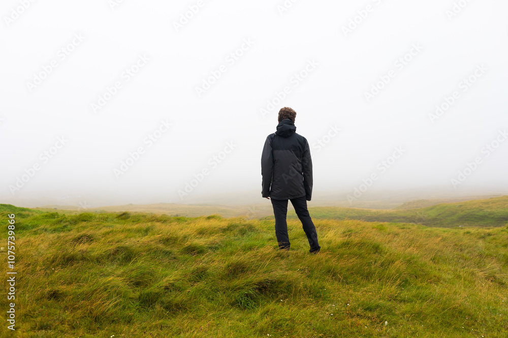 Hiker trekking in foggy Faroe Islands mountains Hiker trekking in foggy Faroe Islands mountains