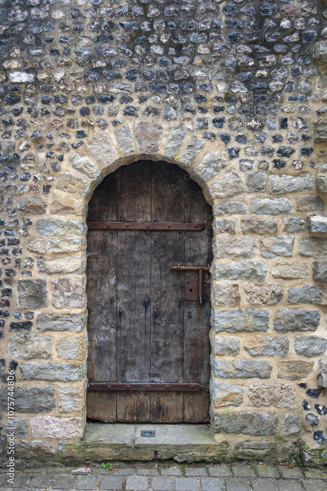 Old arched wooden door with metal fixtures in a stone wall, closse up Old arched wooden door with metal fixtures in a stone wall, closse up