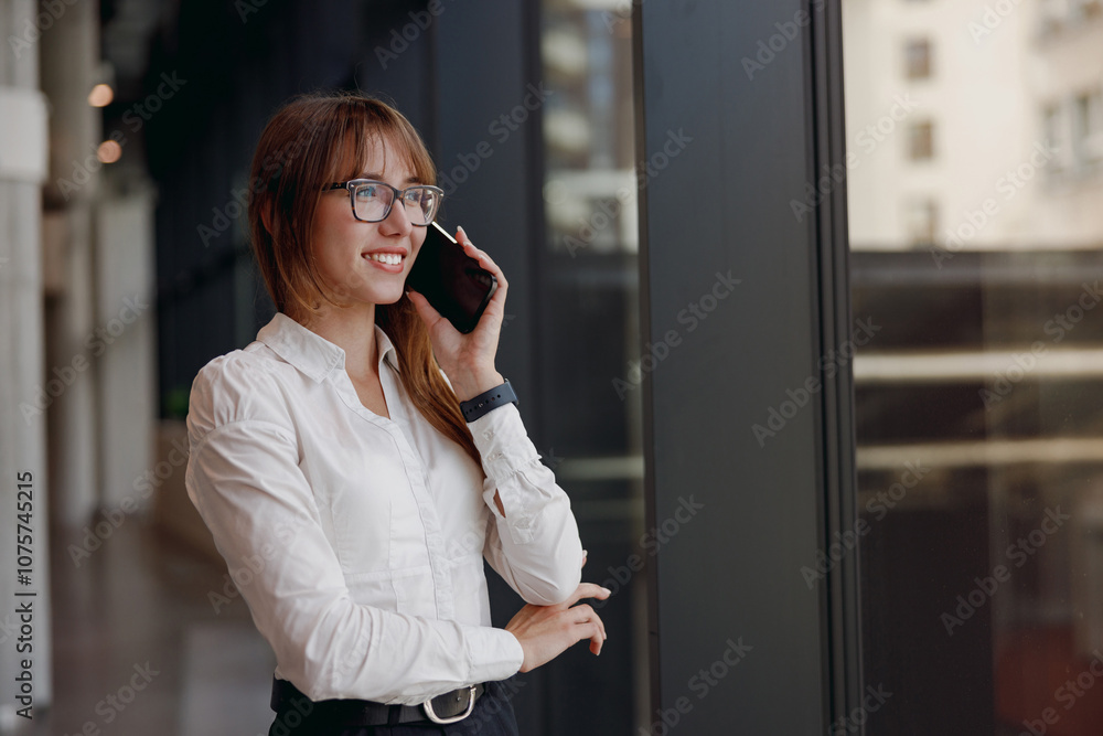 A professional woman engaged in a phone conversation within a stylish and modern office environment setting A professional woman engaged in a phone conversation within a stylish and modern office environment setting