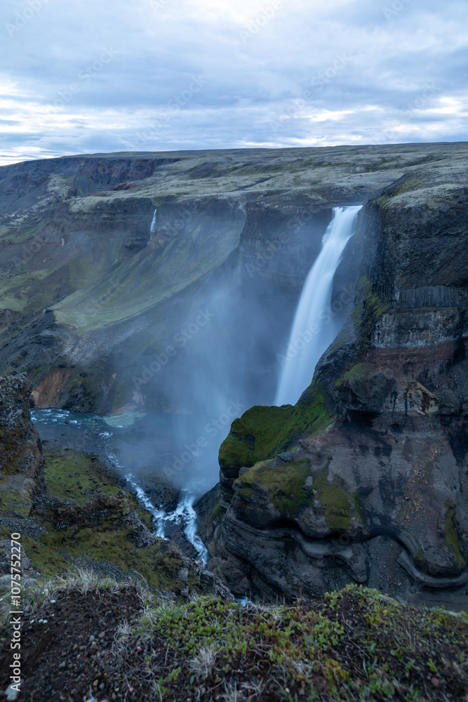Large Waterfall in Iceland coming from cliffs, moody, foggy Large Waterfall in Iceland coming from cliffs, moody, foggy