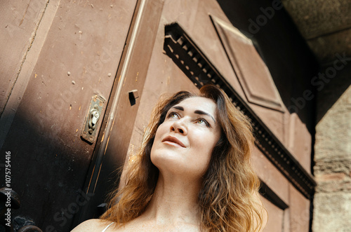 Woman gazing upward in sunlit doorway reflection on a bright day