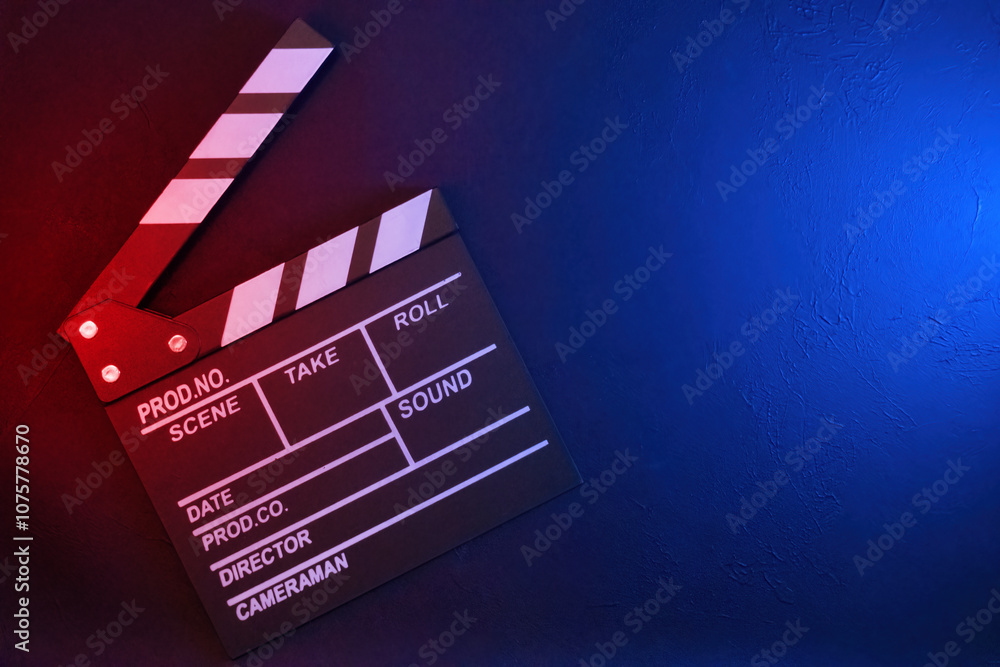 Naklejka premium Clapperboard on black background with red and blue light, top view