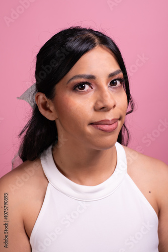 Hispanic woman's face with makeup test on pink background