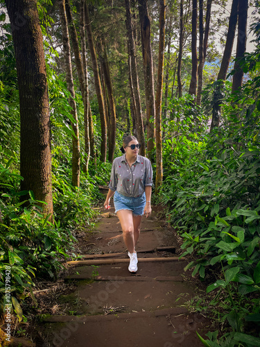 Beautiful Young woman walking up the stairs in the forest, wearing a shirt and shorts. Travel concept. Outdoor lifestyle portrait.