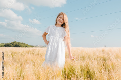 Little girl in a field with hay rolls at sunset.Profile side view little cute happy blond caucasian girl enjoy walking ripe wheat ear field.