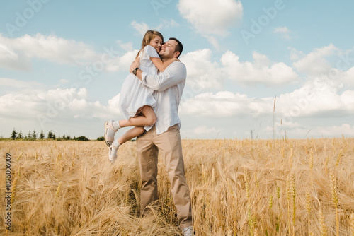 Happy dad kisses his daughter, hugs and holds in his hands.