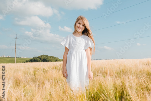 Beautiful little girl laughing and running with hand up in a wheat field against sunset. Freedom concept.