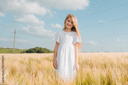 Beautiful little girl laughing and running with hand up in a wheat field against sunset. Freedom concept.