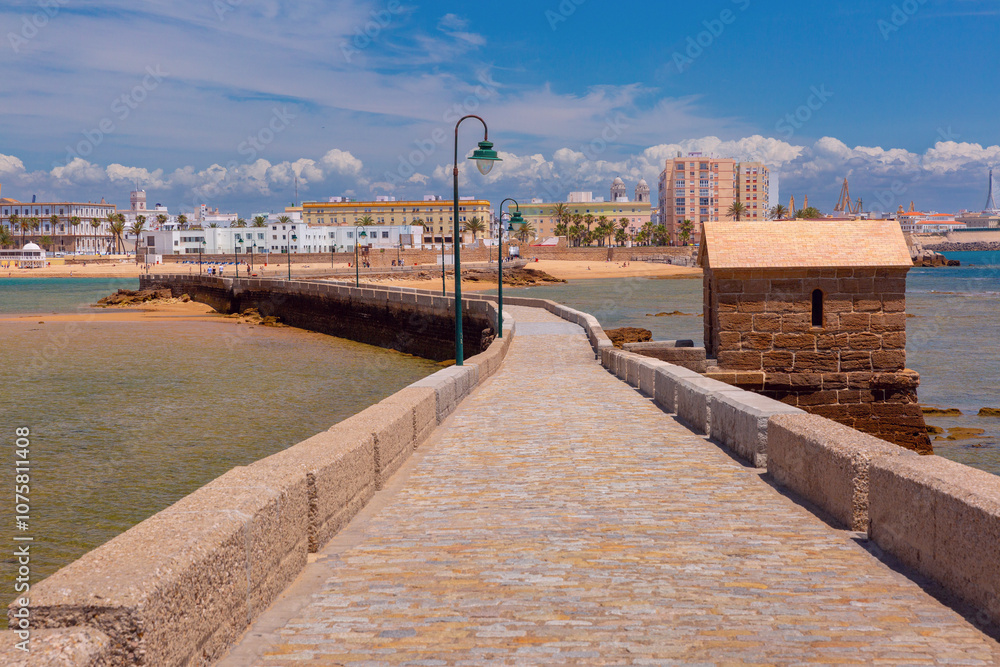 Fototapeta premium Picturesque view of a stone causeway leading across the sandbank to the old fort Castillo de San Sebastian in Cadiz, Spain
