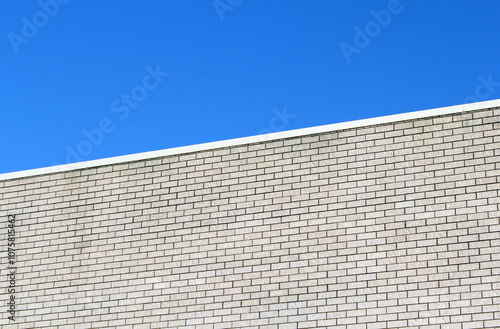 Light-colored brick wall of a building against a blue sky background textured abstract