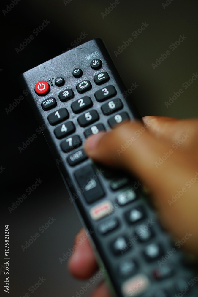 TV remote with red power button, focus selected, blurred background and foreground TV remote with red power button, focus selected, blurred background and foreground