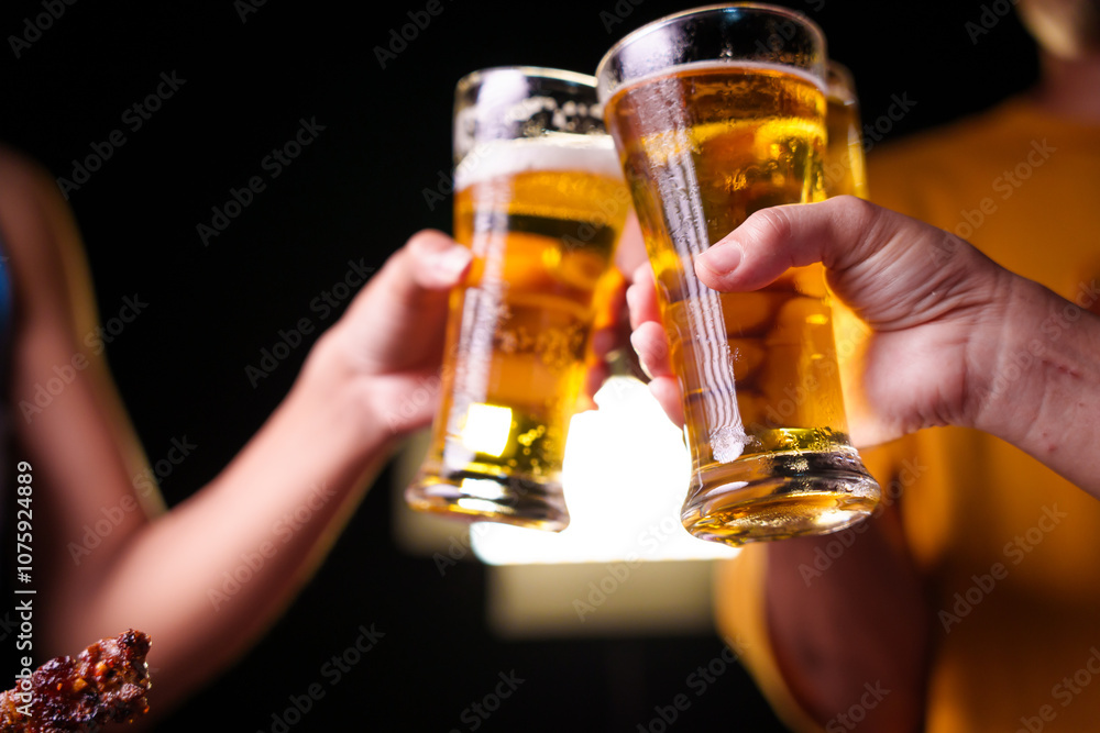 Close-up of friends clinking glasses of beer, celebrating together at a bar.The lively atmosphere captures laughter, camaraderie,good times, as young friends enjoy a night out with refreshing drinks Close-up of friends clinking glasses of beer, celebrating together at a bar.The lively atmosphere captures laughter, camaraderie,good times, as young friends enjoy a night out with refreshing drinks