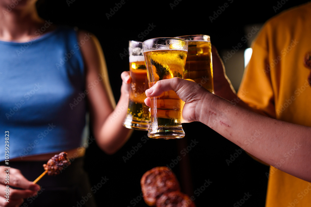Close-up of friends clinking glasses of beer, celebrating together at a bar.The lively atmosphere captures laughter, camaraderie,good times, as young friends enjoy a night out with refreshing drinks Close-up of friends clinking glasses of beer, celebrating together at a bar.The lively atmosphere captures laughter, camaraderie,good times, as young friends enjoy a night out with refreshing drinks