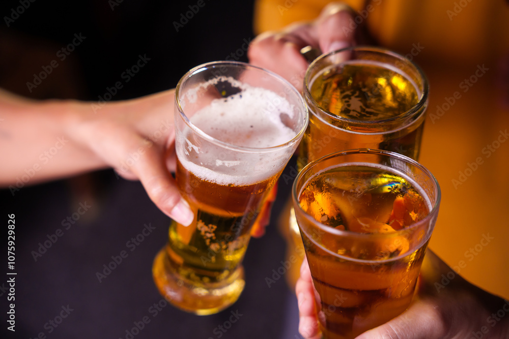 Close-up of friends clinking glasses of beer, celebrating together at a bar.The lively atmosphere captures laughter, camaraderie,good times, as young friends enjoy a night out with refreshing drinks Close-up of friends clinking glasses of beer, celebrating together at a bar.The lively atmosphere captures laughter, camaraderie,good times, as young friends enjoy a night out with refreshing drinks