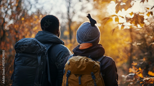 Two hikers enjoy an autumn sunset while exploring a forest trail lined with colorful foliage