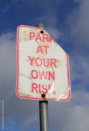 Obraz na plátně Damaged Park At Your Own Risk road sign against a blue sky with clouds backgro