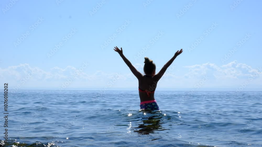 Happy girl having fun and dancing on the beach, enjoying life, swimming. Carefree teenager girl raised hands, dressed in summer attire, bathing suit, deep breathing fresh, cheerfully. Looking up. Happy girl having fun and dancing on the beach, enjoying life, swimming. Carefree teenager girl raised hands, dressed in summer attire, bathing suit, deep breathing fresh, cheerfully. Looking up.