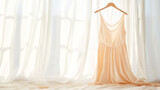 A delicate peach dress hanging against a sunlit, sheer curtain backdrop.