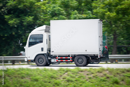 Motion blurred image, of a small white truck for logistics on the roads.