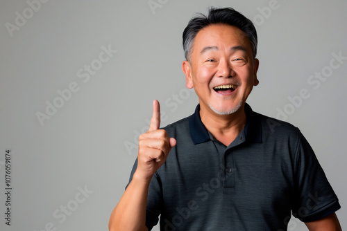 smiling asian man with his fingers up, grey studio background