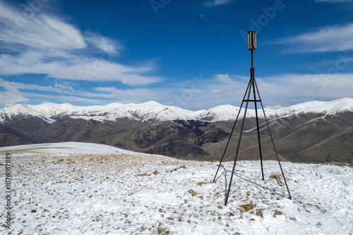 The triangulation point on Mariam summit and Pambak Range cowered with snow on sunny spring day. Aghavnadzor, Armenia. photo